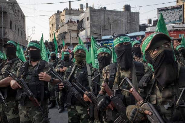 Breaking: Hamas Delays Hostage Release After Accusing Israel of Ceasefire Violations | Epicstorian News Hamas fighters escort Israeli captive Eli Sharabi before transferring him to the Red Cross during a ceasefire exchange.