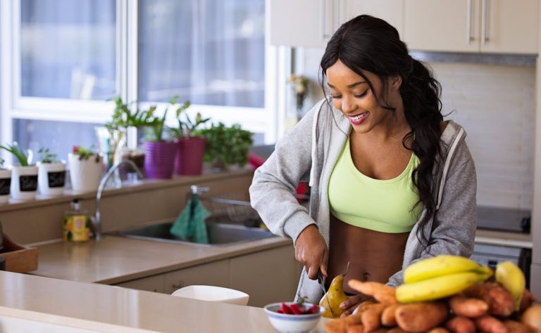 Healthy woman in a neat kitchen preparing potatoes with plantains and peppers in front
