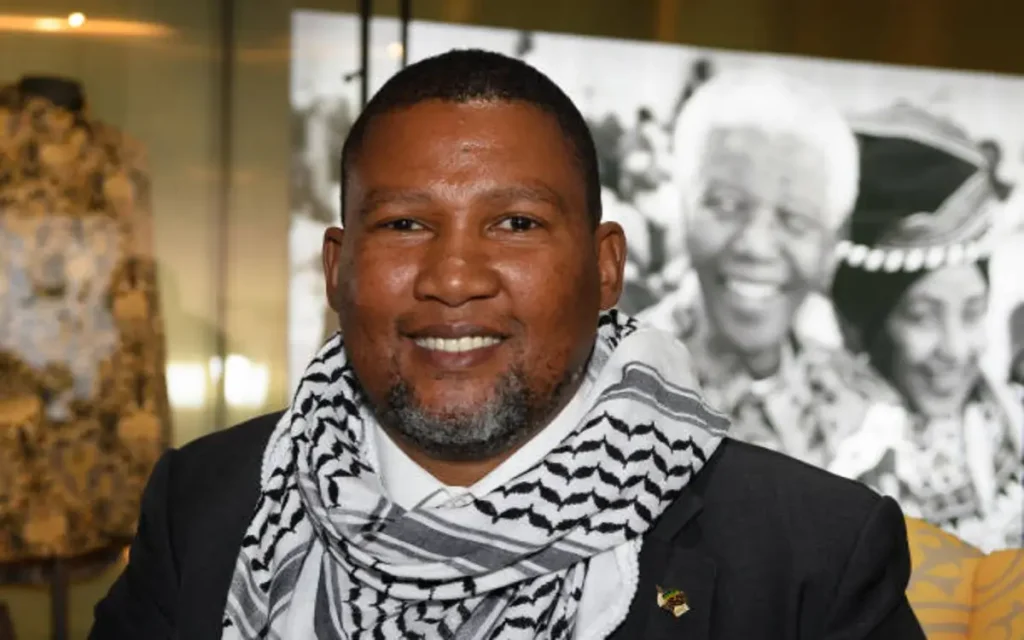 Mandela’s Grandson Returns to South Africa After Deportation by Israel | Epicstorian News Mandela’s grandson walks with wife at Johannesburg airport after deportation, greeted by supporters waving Palestinian flags and banners.