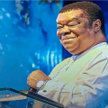 Portrait of Rev. Uma Ukpai smiling with background of church logo and congregation