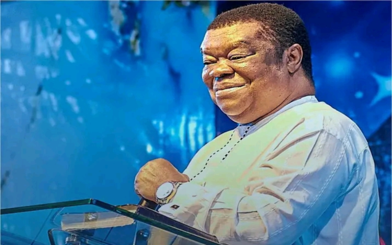 Portrait of Rev. Uma Ukpai smiling with background of church logo and congregation