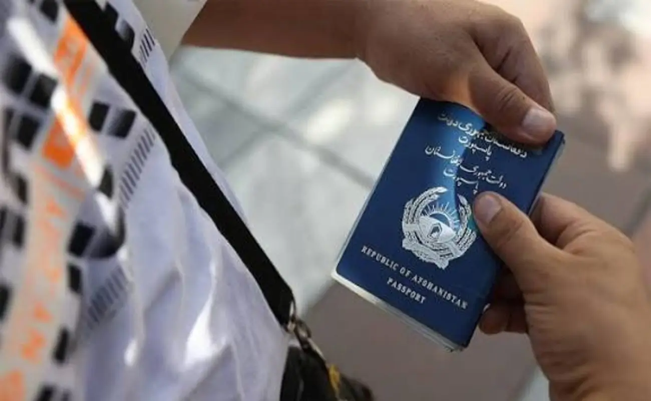 Afghan national holding passport booklet during US federal suspension of Afghan immigration processing after Washington DC shooting.