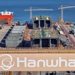Overview of Hanwha Ocean Geoje shipyard in South Korea showing large cranes and ship modules under construction