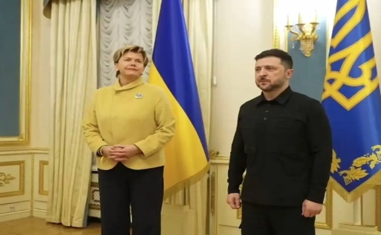 Zelenskyy and Latvia's foreign minister shake hands and smile for the camera during official meeting in Kyiv.