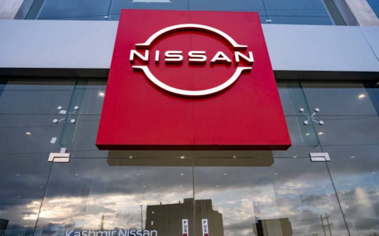 A worker cleans a Nissan badge at Nissan Kyushu plant amid Japan vehicle production and semiconductor shortages.