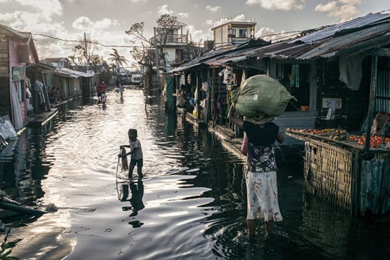 A woman wades the flooded neighborhood with her child ilafter Cyclone Gezani struck Madagascar on February 12, 2026
