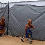 Palestinian children sit at desks attending class inside a temporary caravan school in Gaza City amid post-conflict education recovery efforts