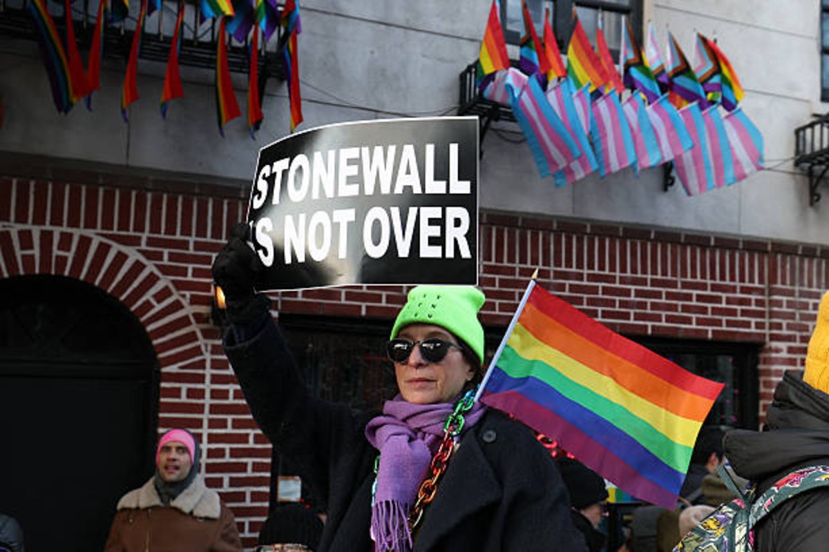 New York Officials Re-Raise LGBTQ Pride Flag After NPS Removal | Epicstorian News Person holding sign during Pride flag re-raising ceremony at Stonewall National Monument in Manhattan